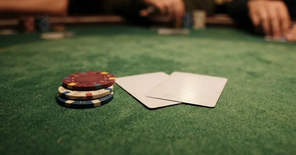 A close-up of a green felt gaming table with cards and chips mid-hand.