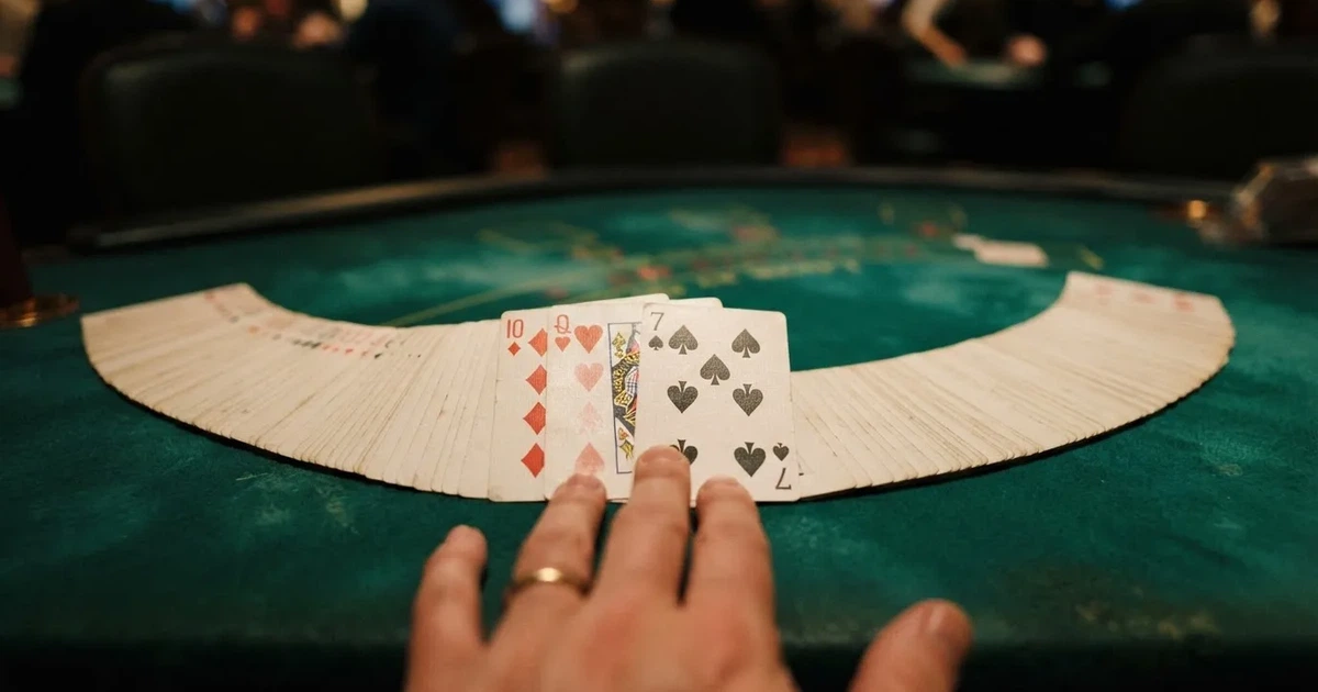 A close-up of a shuffled deck of playing cards fanned out on a green felt table.